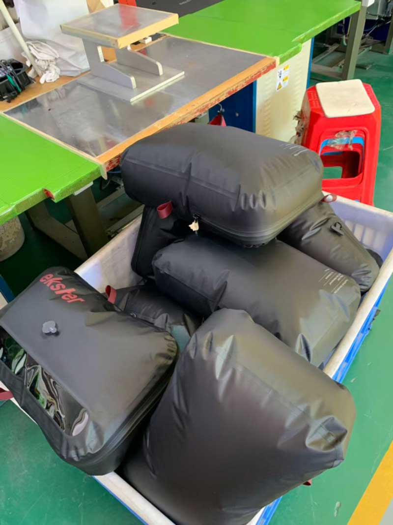 Inflated welded bags held in a cloth-lined bin next to a high-frequency welding station